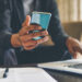 Man Taking notes on a phone computer and paper